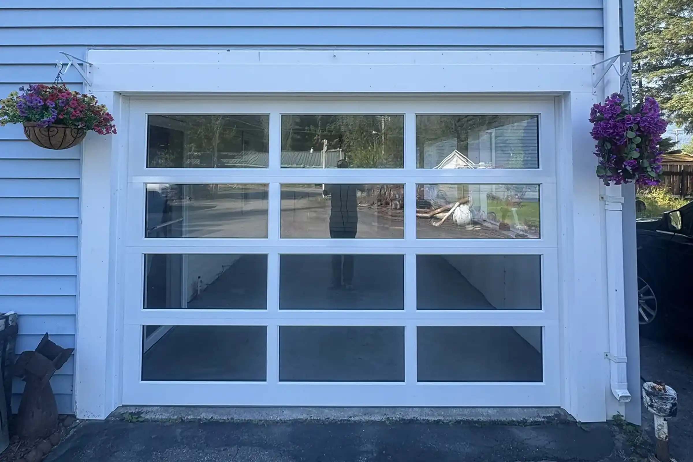 White full-view glass garage door on a light blue home