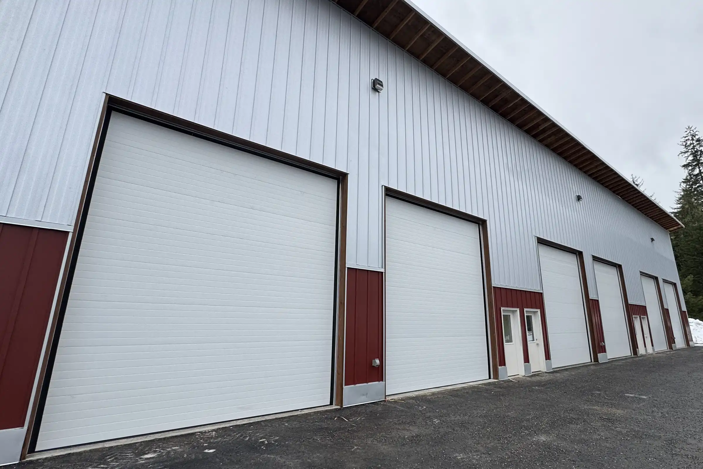 White commercial garage doors on a multi-bay metal building with red trim