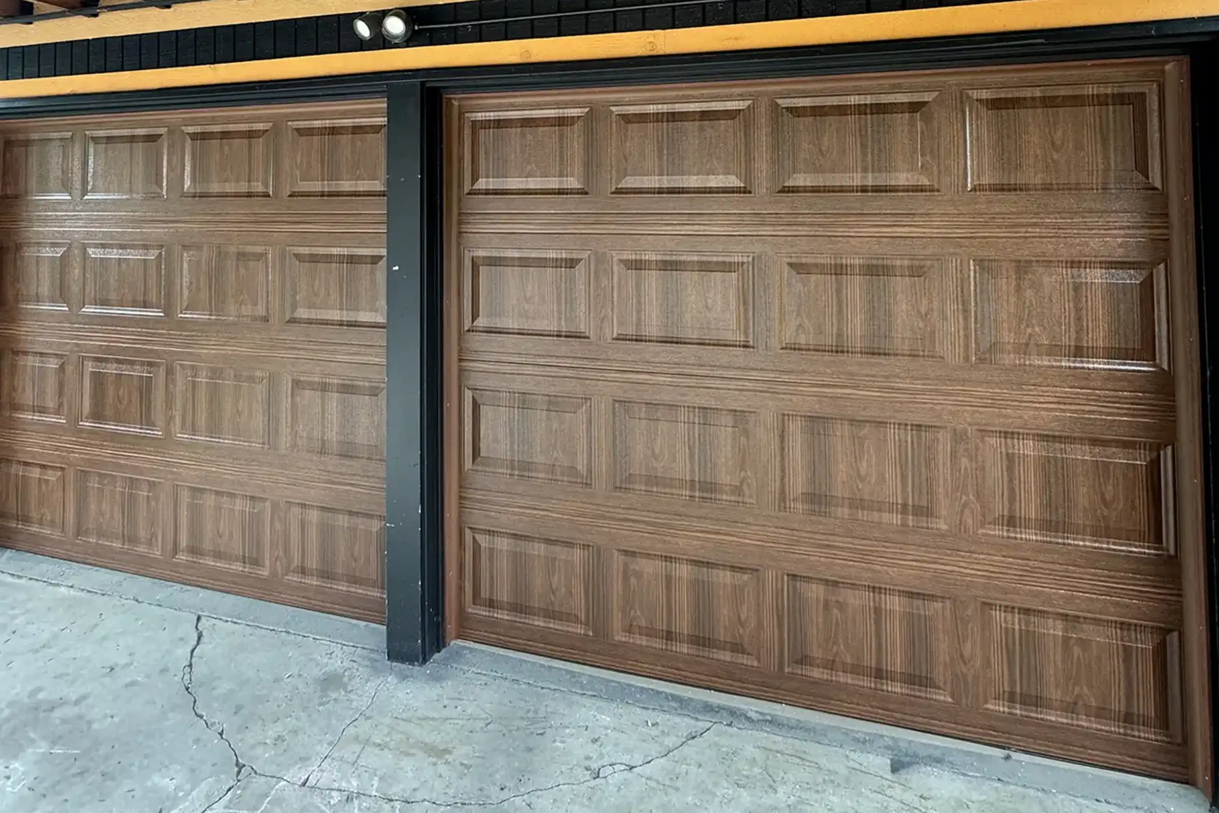 Wood-grain raised-panel double garage doors under a timber carport